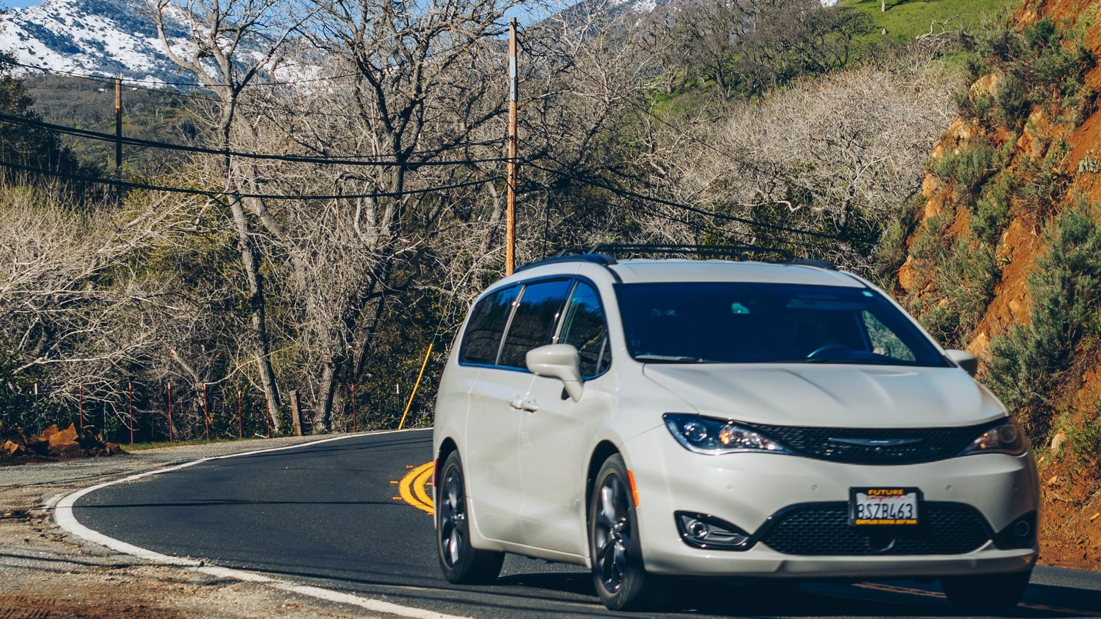 Minivan blanca circulando por una carretera de montaña