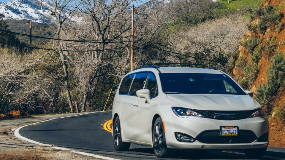 Minivan blanca circulando por una carretera de montaña