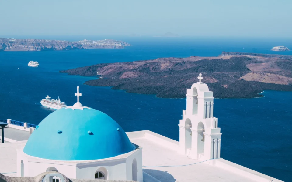 Cúpula azul y campanario en Santorini con vistas al mar Egeo